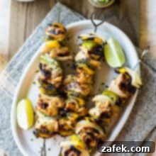 Overhead photo of chicken skewers on a white oval plate on a wooden board