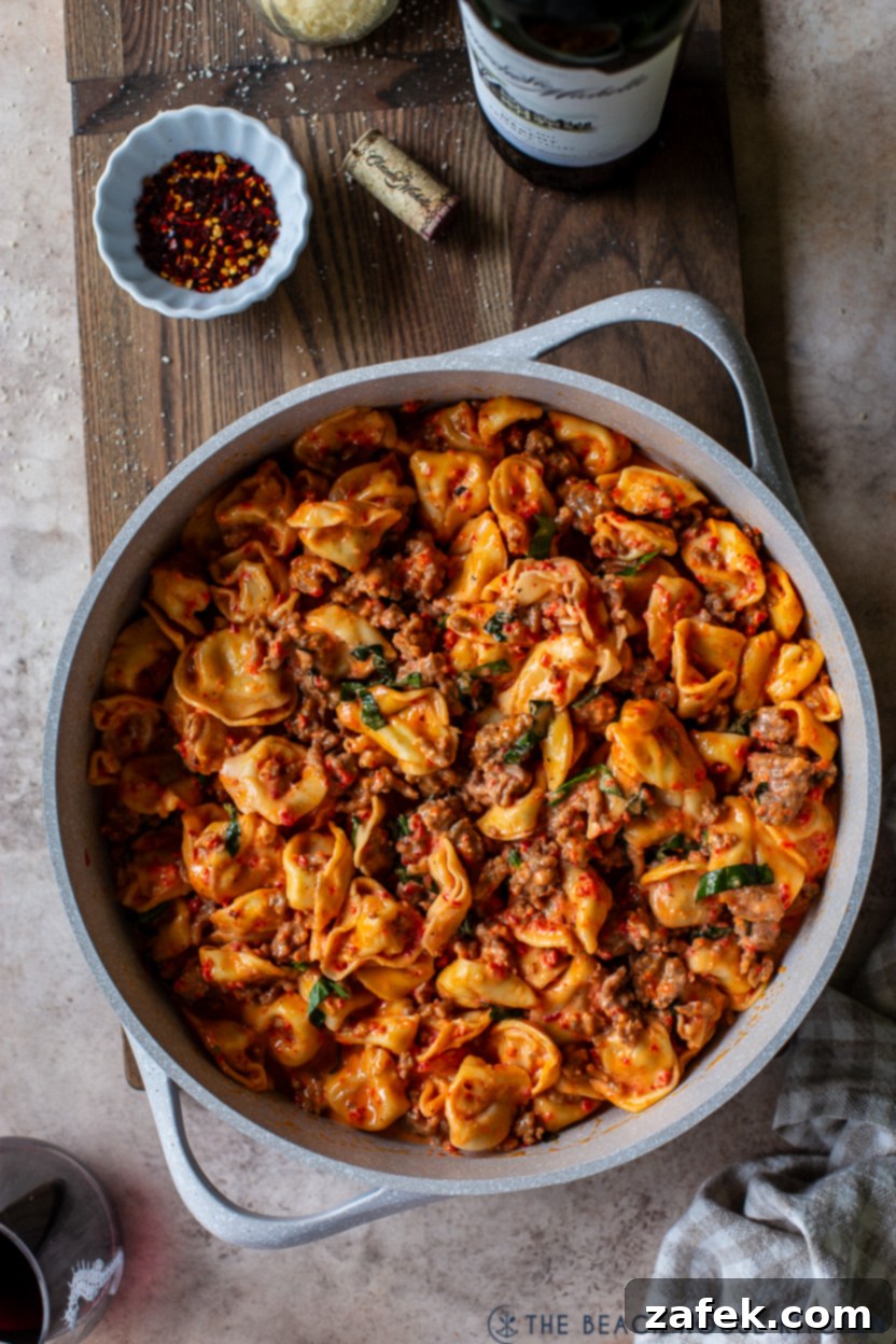 Overhead photo of a skillet of Roasted Red Pepper Tortellini Alfredo with Sausage
