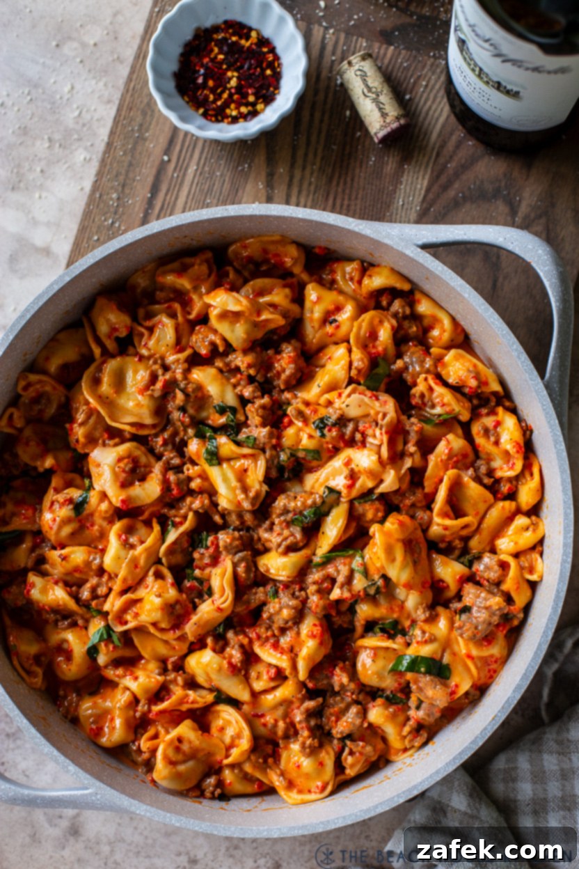 Up close overhead photo of a skillet of Roasted Red Pepper Tortellini Alfredo with Sausage 