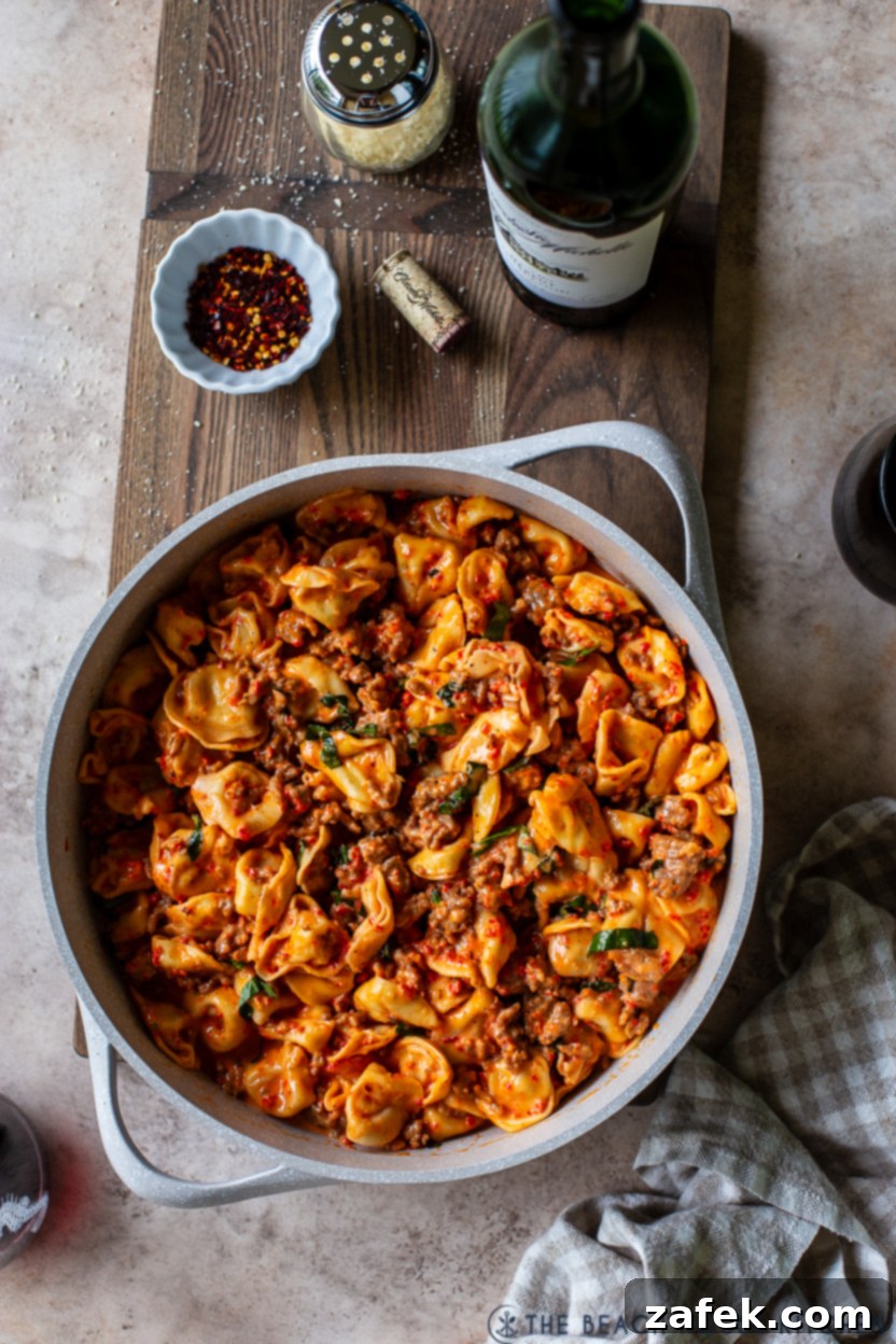 Overhead photo of a skillet of Roasted Red Pepper Tortellini Alfredo with Sausage