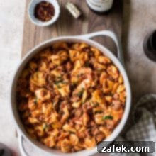 Overhead photo of pan filled with roasted red pepper tortellini alfredo with Italian Sausage