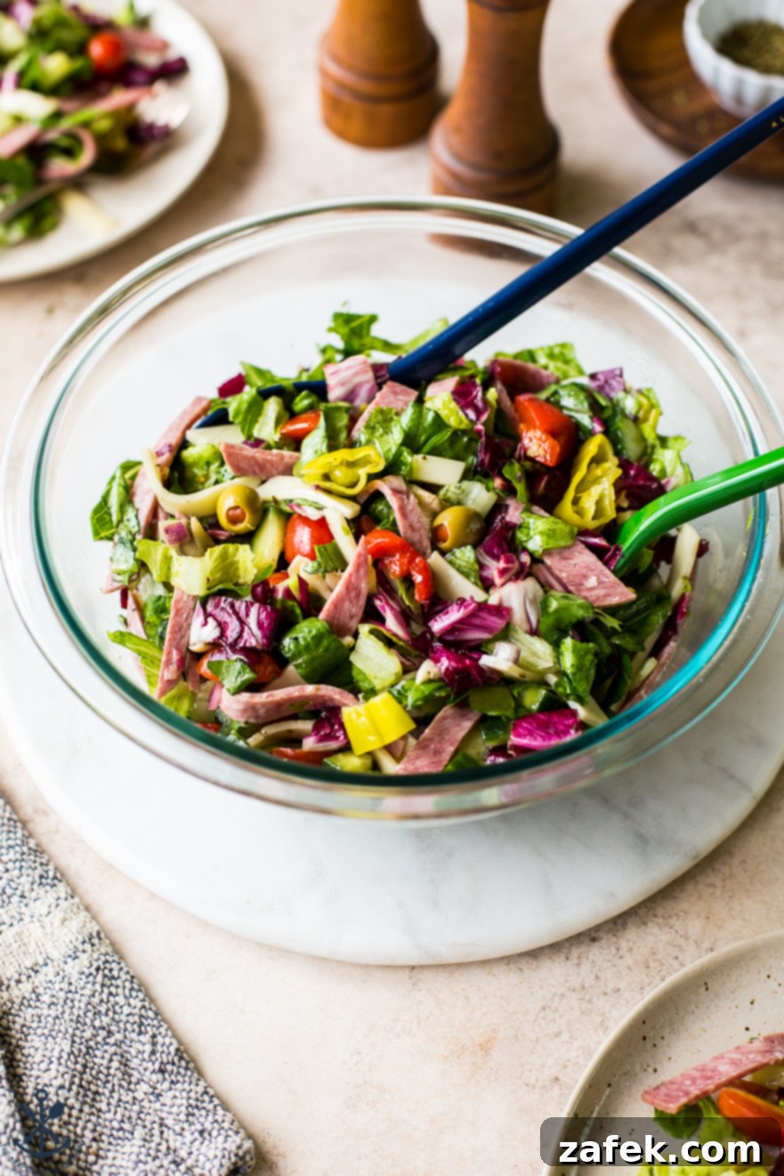 Delicious Italian Chopped Salad in a clear glass bowl on a pristine white marble board, ready to be enjoyed.