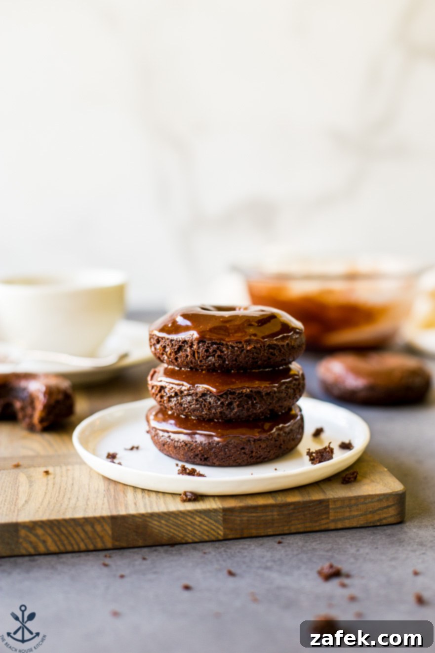 Baked Mocha Donuts 2 Delicious stack of three homemade cocoa coffee baked donuts on a crisp white plate, showcasing their rich chocolate color and inviting texture.