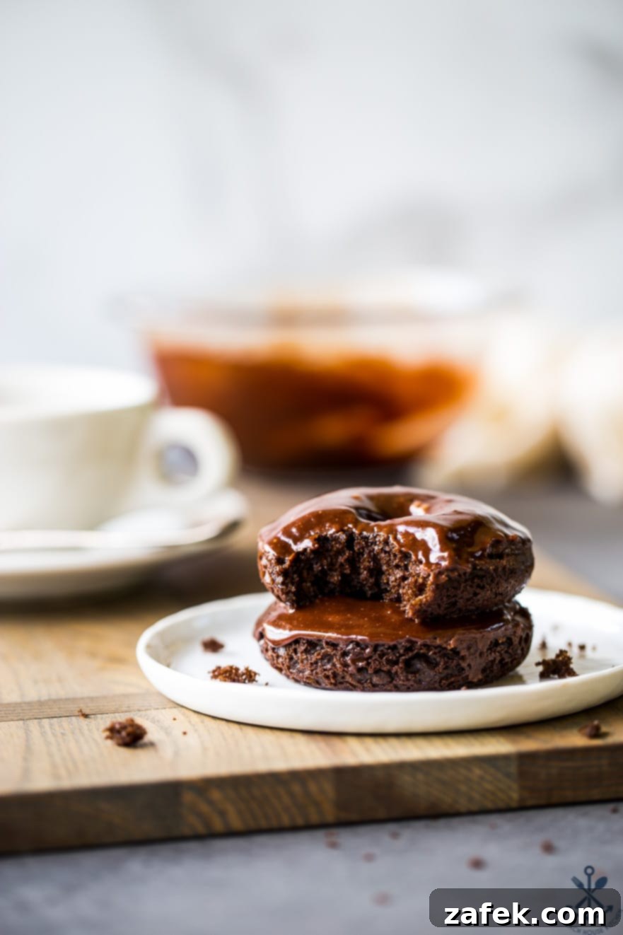 Baked Mocha Donuts 9 Two beautifully glazed cocoa coffee baked donuts stacked on a simple white plate, inviting a delicious treat.