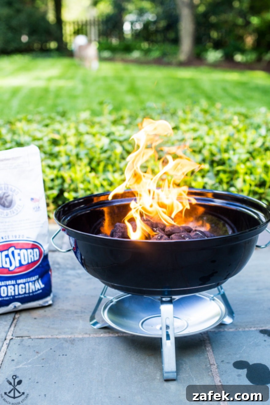 Small grill with fire and a bag of charcoal behind it