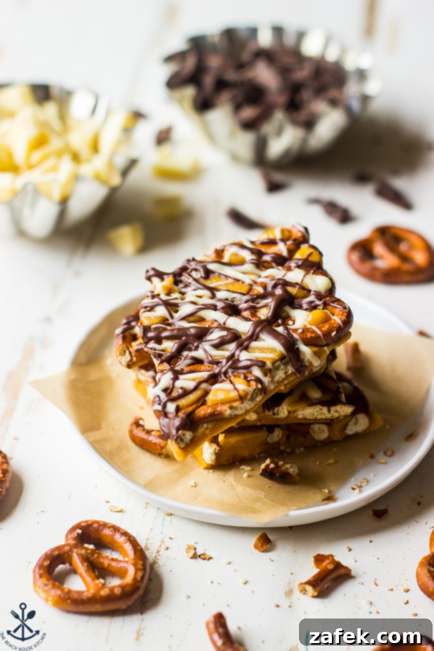 Pretzel toffee on a small white plate with pretzels and pretzel crumbs around it, highlighting its irresistible texture.