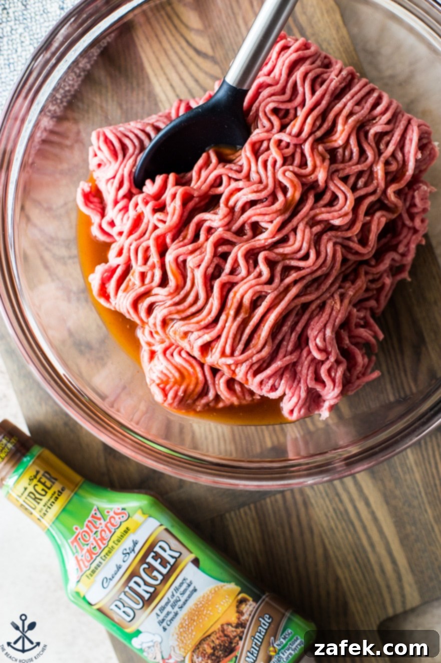 Ground beef in a glass bowl next to a bottle of Tony Chachere's Burger Marinade, showcasing key ingredients