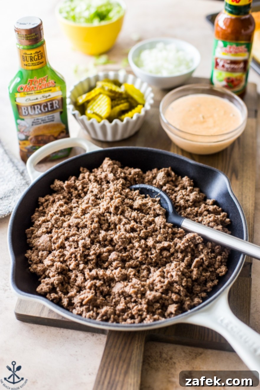 A skillet filled with cooked, seasoned hamburger meat, ready for slider assembly