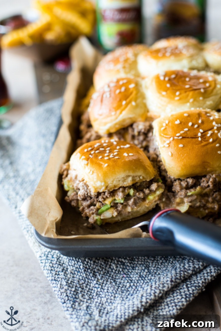 A baking tray filled with assembled Tony's Baked Cheeseburger Sliders, topped with sesame seeds and ready for the oven