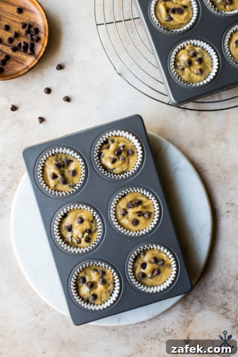 Effortless Chocolate Chip Muffins 5 Overhead photo of pre-baked chocolate chip muffins in a muffin pan, showing raw batter