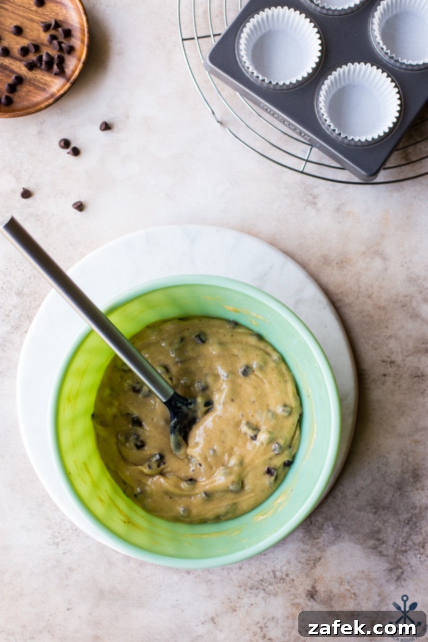 Effortless Chocolate Chip Muffins 8 Overhead photo of a bowl filled with chocolate chip muffin batter, showing chocolate chips folded in