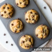 Effortless Chocolate Chip Muffins 9 Overhead photo of Easy Chocolate Chip Muffins in muffin tin on a round white marble board