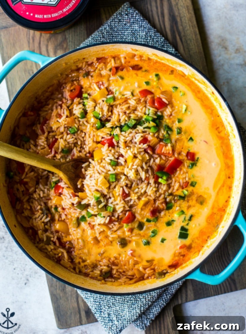 Overhead photo of a skillet filled with pre-mixed cheesy queso fiesta rice, showcasing the vibrant colors of peppers and a creamy texture