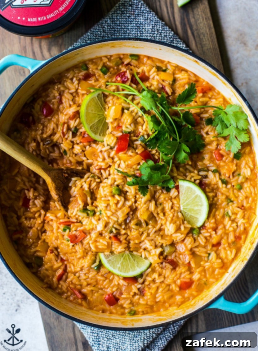 Up close overhead photo of a skillet overflowing with creamy, vibrant cheesy queso fiesta rice, garnished with fresh cilantro, ready to be enjoyed