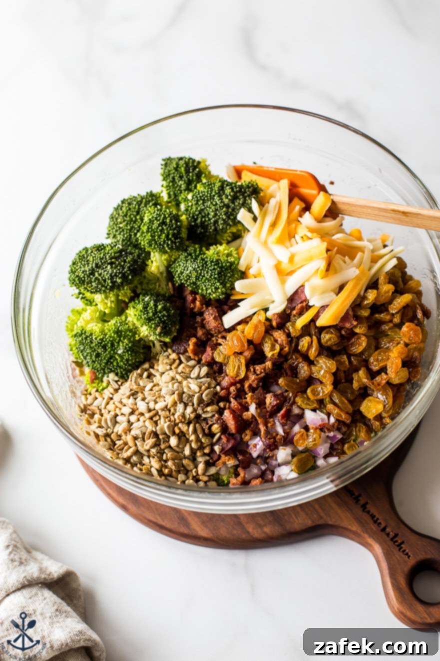Ingredients for classic broccoli salad with bacon laid out in a glass bowl, showing fresh produce
