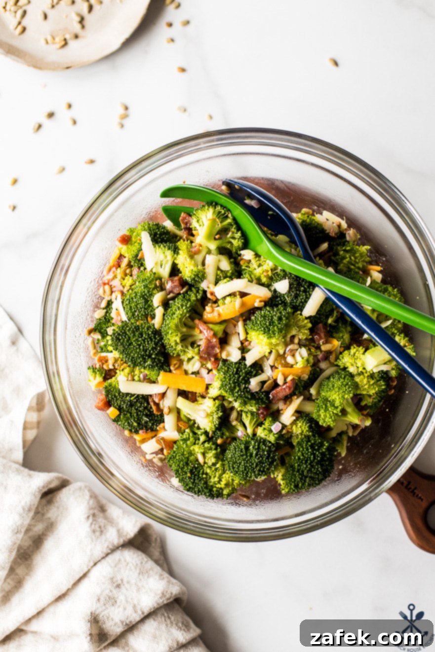 Overhead photo of classic broccoli salad with bacon in a large glass bowl, garnished and ready to serve