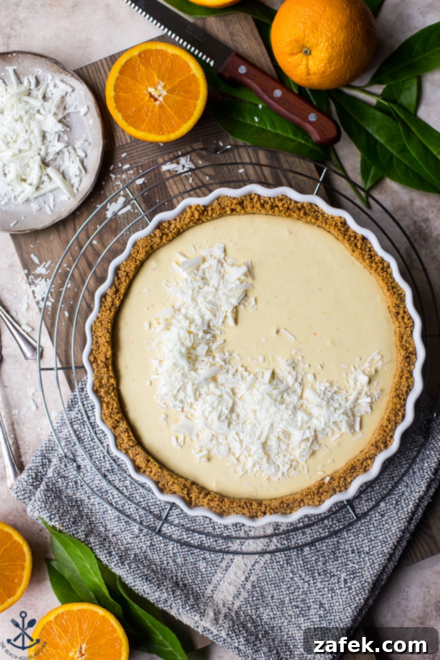 Zesty Orange Cream Tart 2 Overhead photo of an orange cream tart on a round wire rack surrounded by halved oranges, highlighting its vibrant color and fresh appeal.