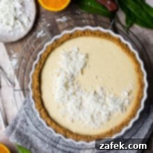 Zesty Orange Cream Tart 9 Overhead photo of an orange cream tart on a round wire rack surrounded by halved oranges, serving as the main recipe image.
