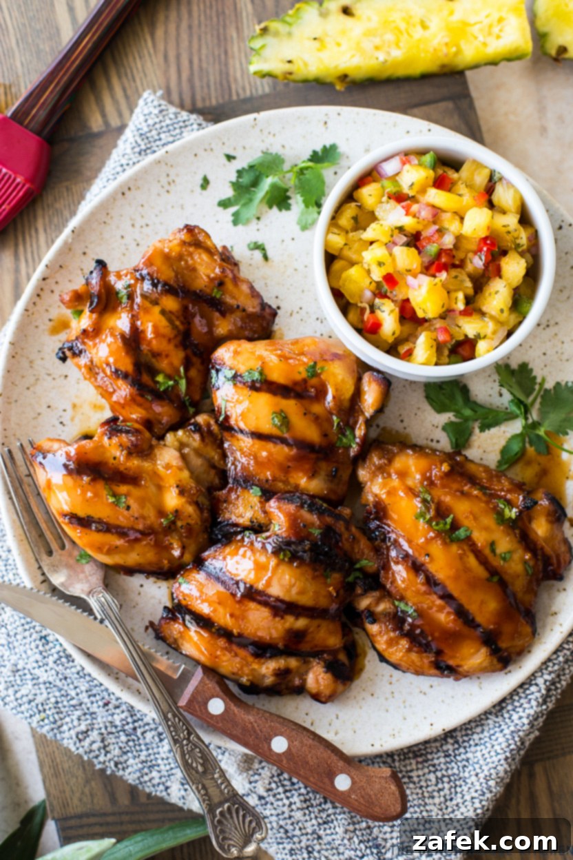 Tropical Huli Huli Chicken with Zesty Pineapple Salsa 2 Up close overhead photo of grilled Huli Huli chicken on a plate with fresh pineapple salsa, garnished with cilantro.