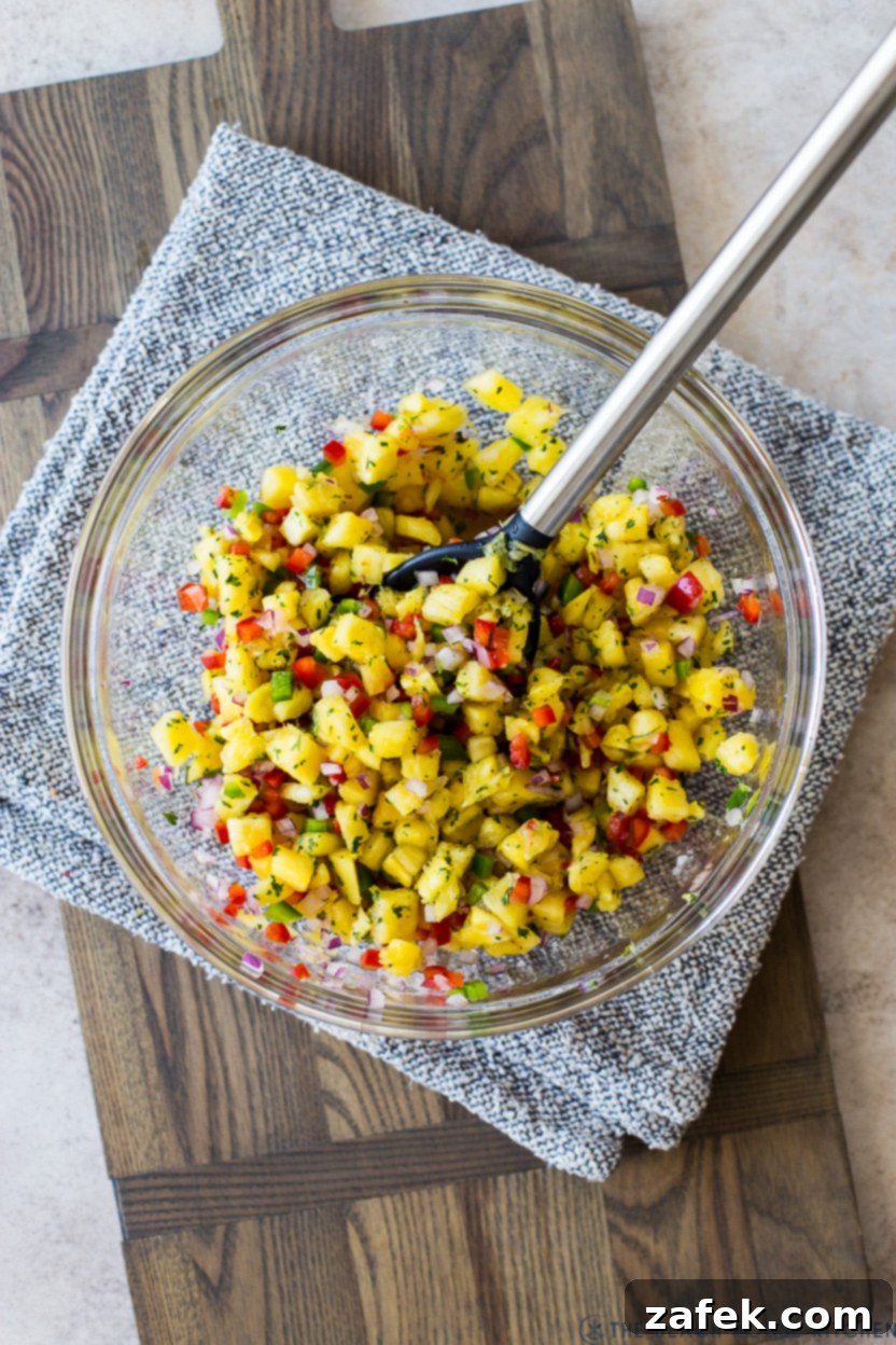 Tropical Huli Huli Chicken with Zesty Pineapple Salsa 6 Overhead photo of a clear glass bowl filled with vibrant pineapple salsa, garnished with fresh cilantro.