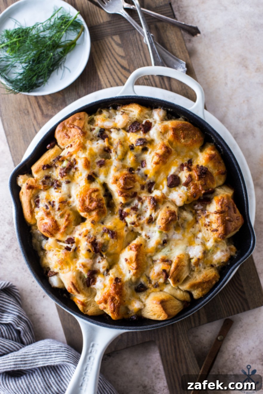 Overhead photo of delicious Cheesy Shrimp Skillet Monkey Bread in a white skillet on a rustic wood board, ready to be enjoyed as a crowd-pleasing appetizer.