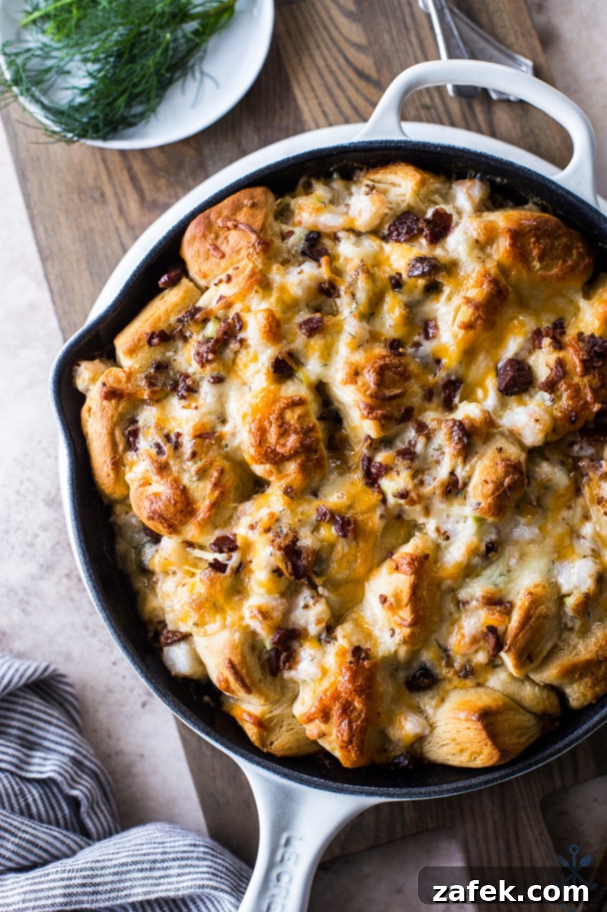 Close-up shot of Cheesy Shrimp Skillet Monkey Bread in a white skillet on a wooden board, showcasing its golden-brown biscuits and melted cheese.