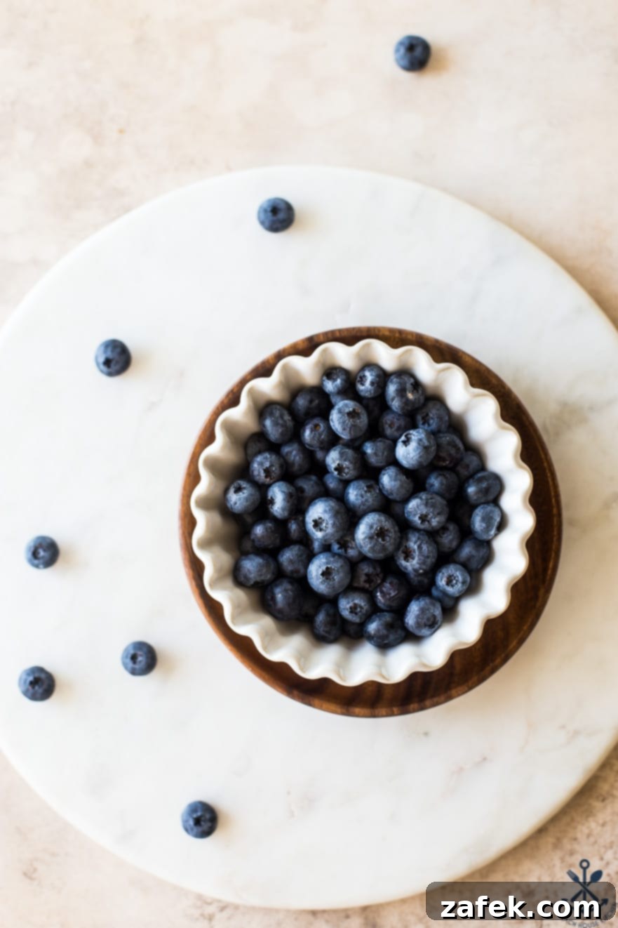 Velvet Blueberry Ice Cream 6 Overhead photo of blueberries in a white scalloped bowl on a round marble board