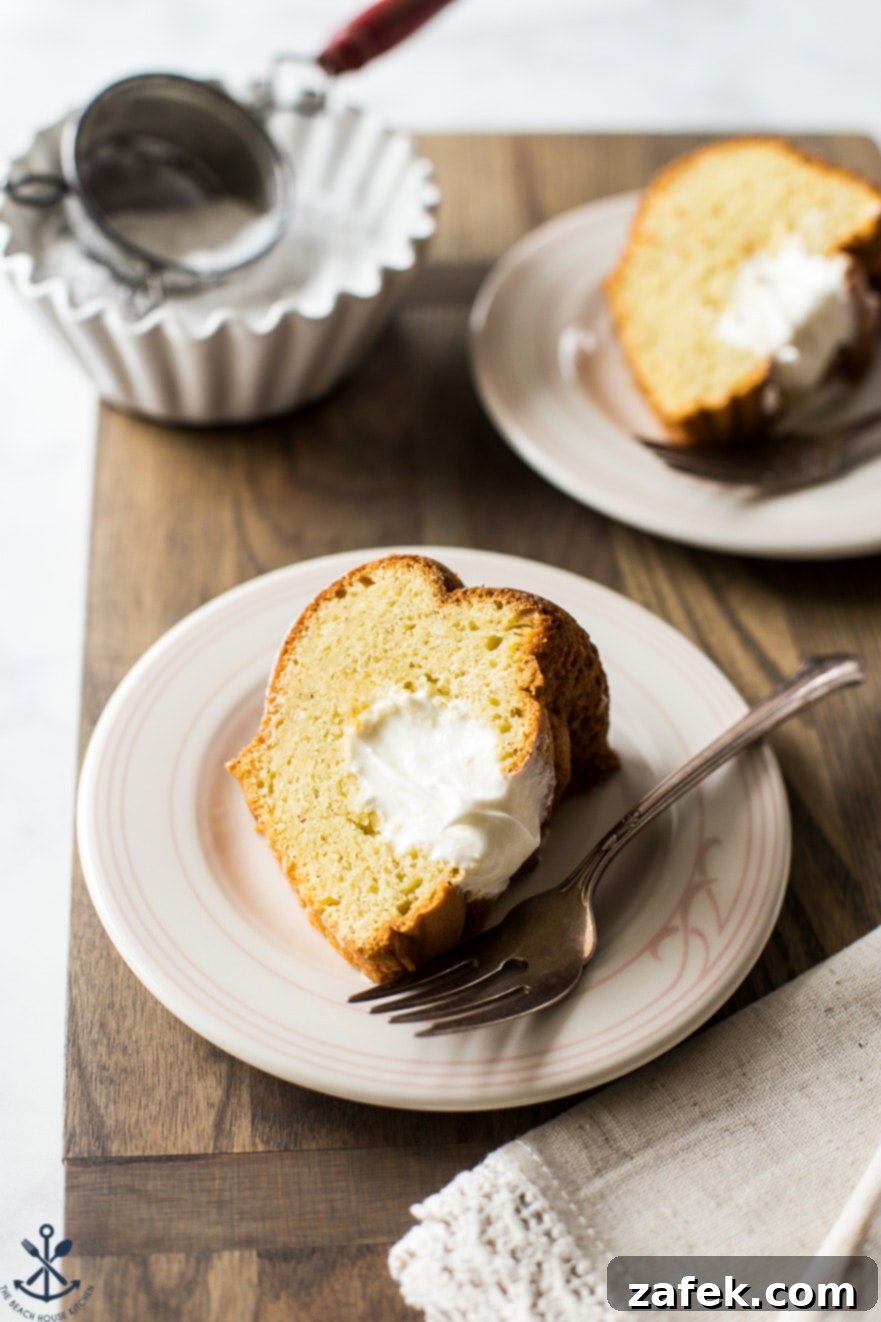 A perfectly sliced piece of Easy Twinkie Bundt Cake on a small white plate, revealing its moist texture and creamy marshmallow filling, set against a rustic wooden board.
