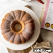 Overhead photo of Easy Twinkie Bundt Cake on a white cake plate on a wooden board