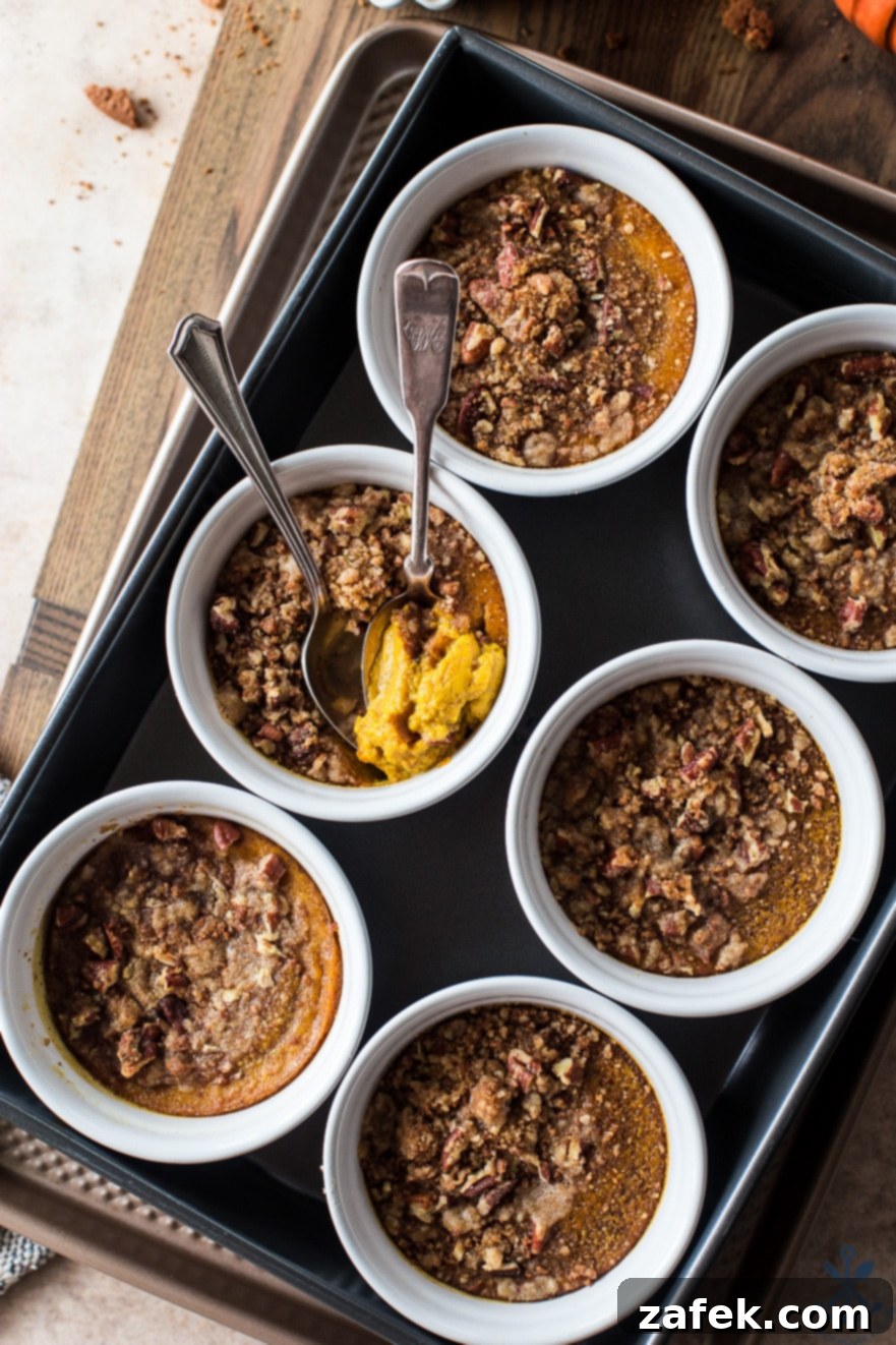 Spiced Pumpkin Custards with Gingersnap Crumble 3 Close-up of baked Pumpkin Custards with Gingersnap Crumble in elegant white ramekins, ready to be served.