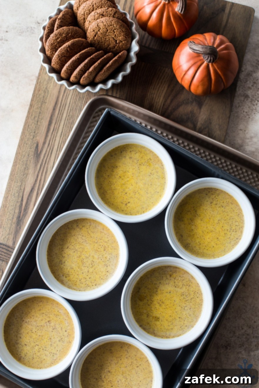 Spiced Pumpkin Custards with Gingersnap Crumble 5 Unbaked pumpkin custards neatly arranged in white ramekins, ready for their journey into the oven and a water bath.