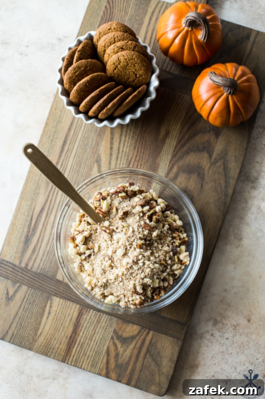 Spiced Pumpkin Custards with Gingersnap Crumble 8 A bowl filled with gingersnap crumble, ready to be sprinkled over the pumpkin custards, elegantly presented on a rustic wooden board.