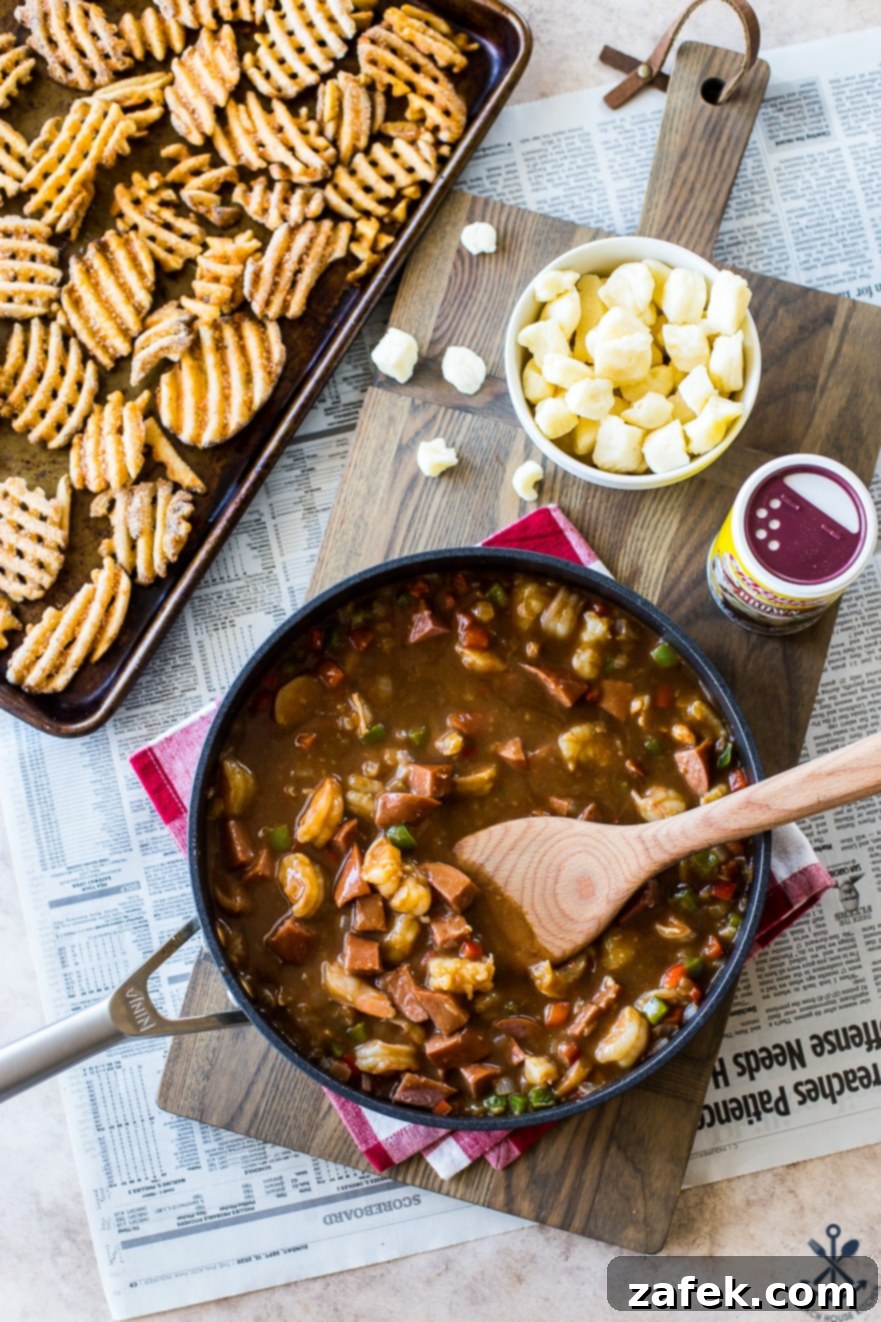 Bayou Poutine 4 Overhead photo of gravy for Cajun poutine in a skillet with a bowl of cheese curds and a tray of waffle fries