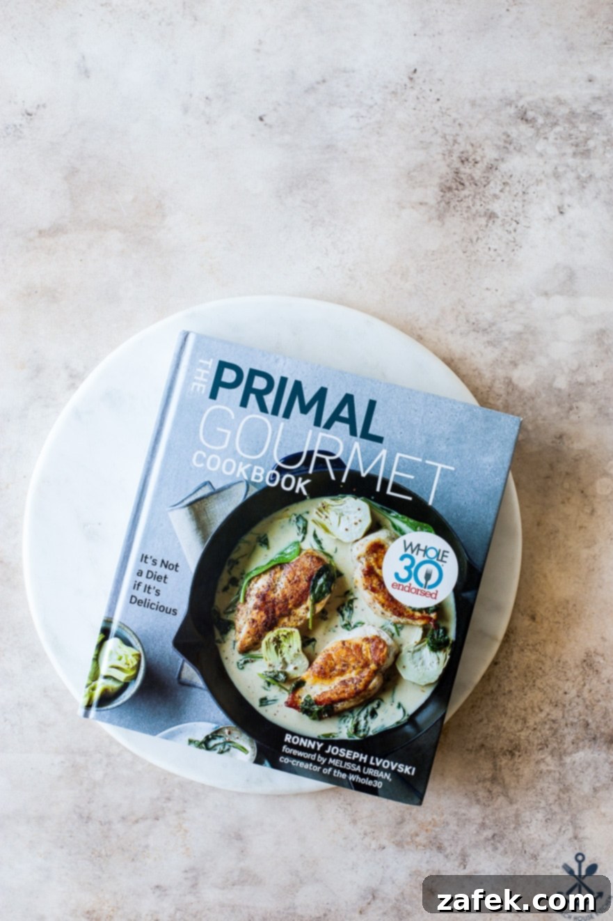 Unforgettable Short Rib Ragù Unmissable Giveaway 3 Overhead shot of The Primal Gourmet Cookbook resting on a elegant round marble board, inviting readers to explore its pages.