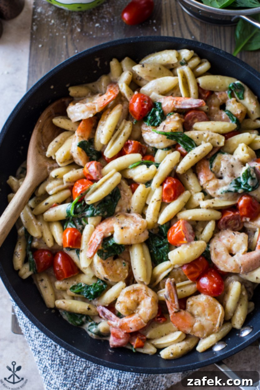 Creamy Garlic Shrimp Pasta with Sun-Kissed Tomatoes and Tender Spinach 3 Close-up overhead photo of a skillet brimming with cooked Shrimp Pasta, showcasing the creamy sauce, plump shrimp, red tomatoes, and green spinach beautifully mixed.