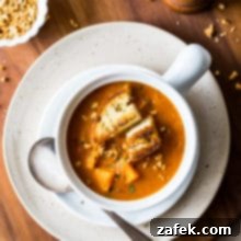 West African Peanut Sweet Potato Stew 7 Overhead photo of African peanut sweet potato stew in a white bowl on a white plate on a wooden board.