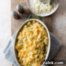 Potatoes Romanoff in an oval baking dish with a plate of shredded cheese and a grater