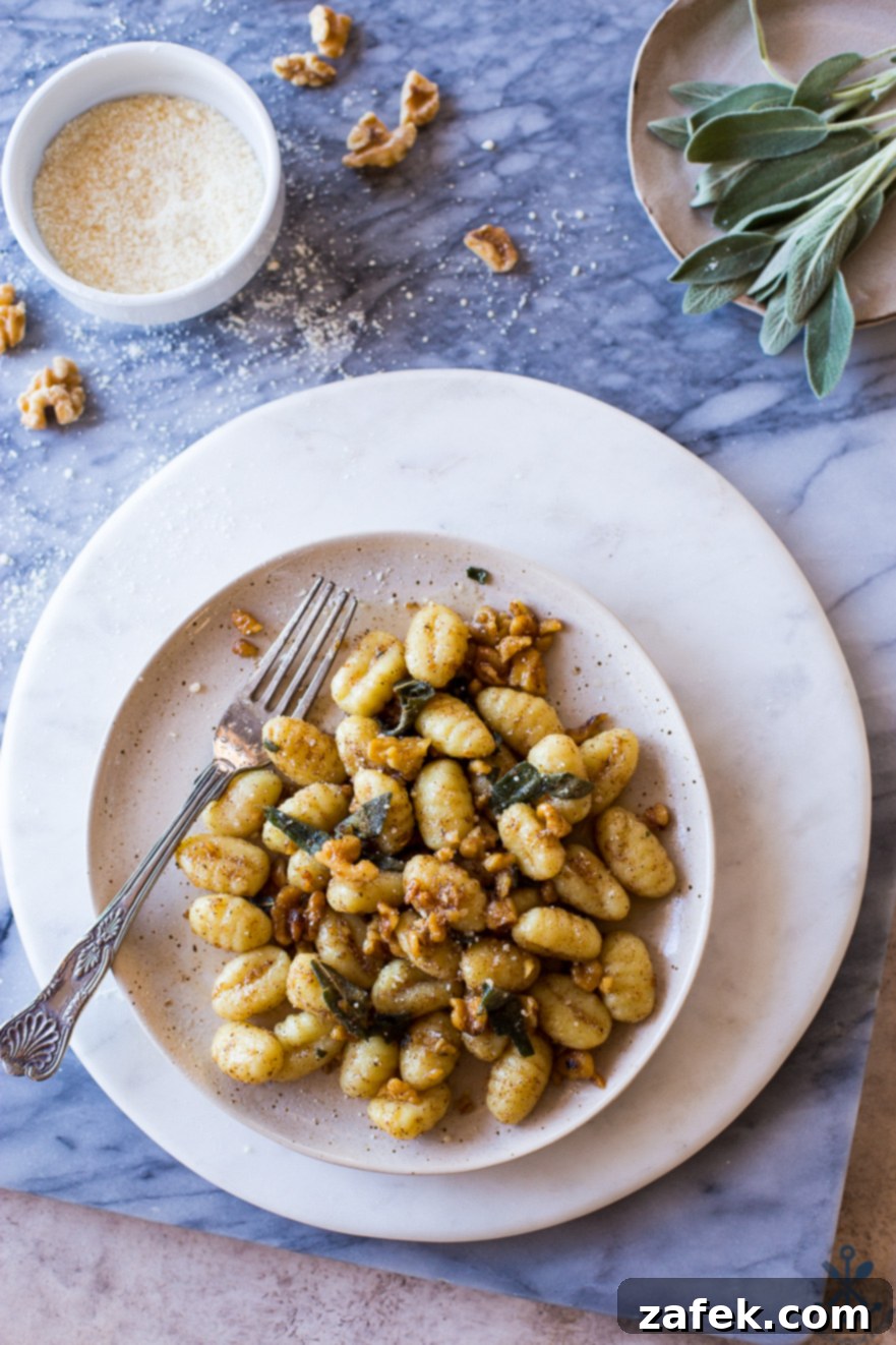 Sage-Kissed Gnocchi with Toasted Walnut Brown Butter 2 Overhead photo of a plate of Gnocchi with Walnut Brown Butter Sage Sauce on a marble board with sage leaves on a plate