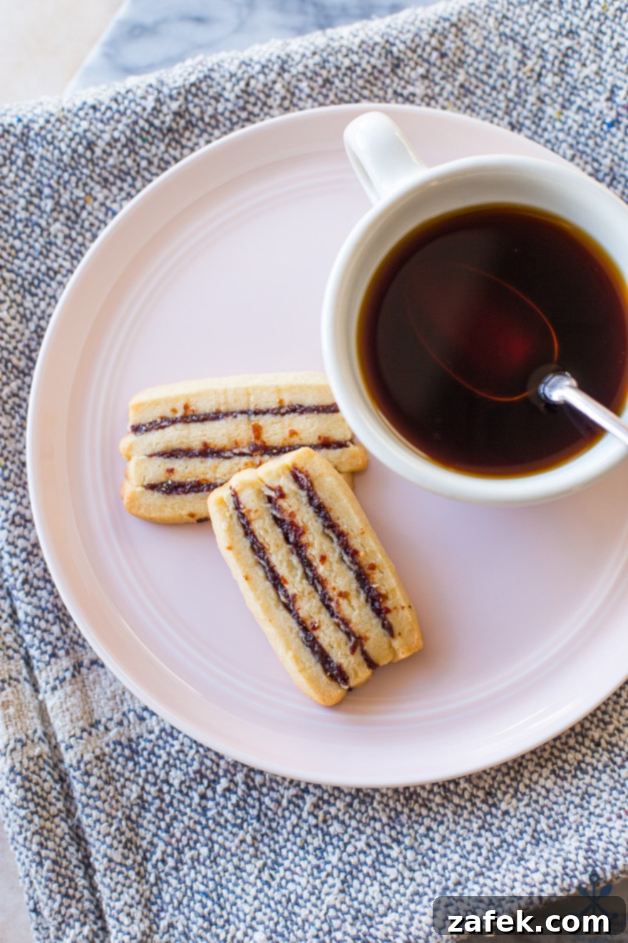 Two Cherry Ribbon Butter Cookies on a pink plate with a cup of coffee