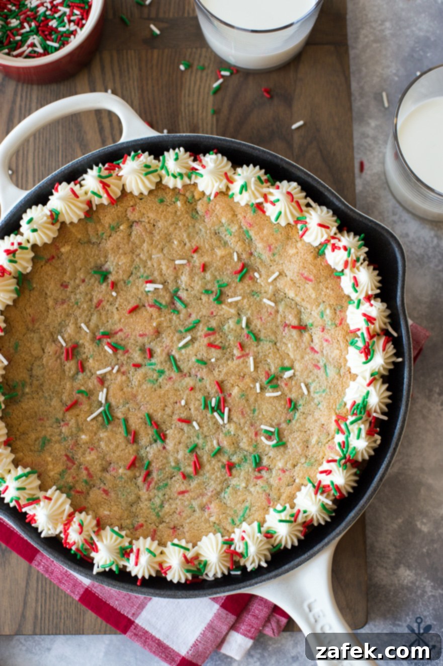 One-Pan Holiday Funfetti Cookie Bliss 2 Overhead photo of Easy Holiday Funfetti Sugar Cookie Skillet on a wooden board, decorated with vanilla icing and extra sprinkles