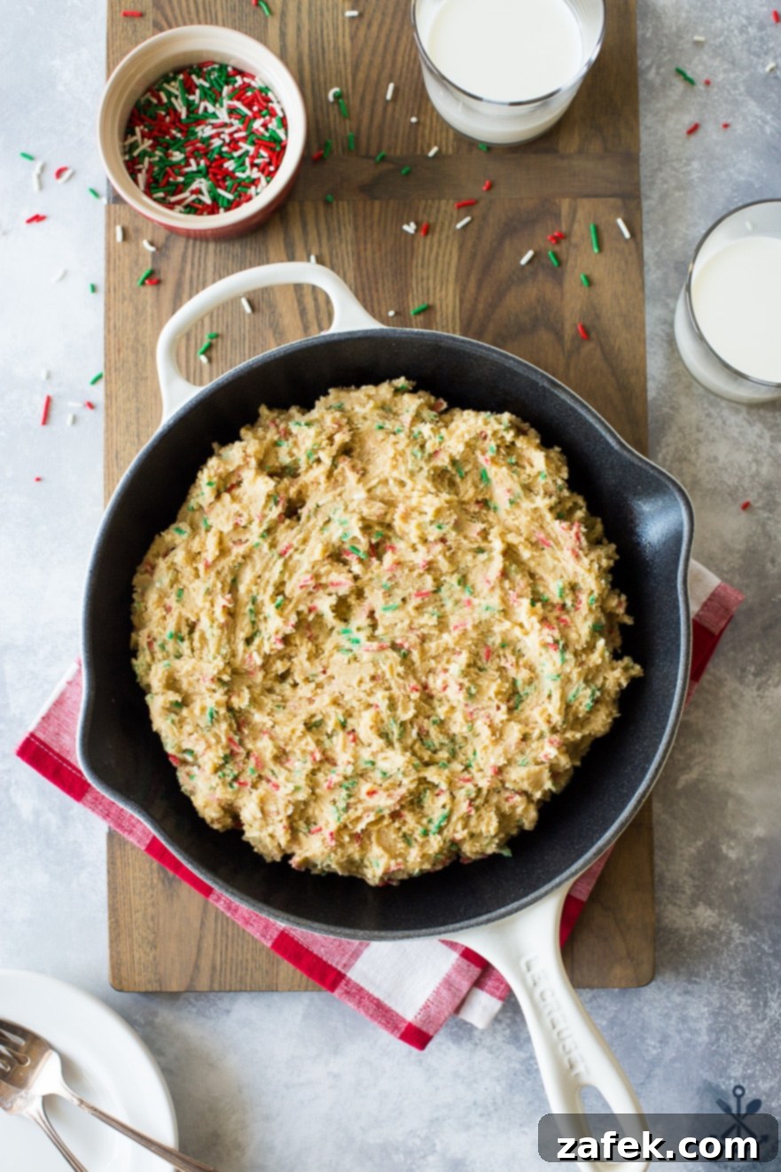 One-Pan Holiday Funfetti Cookie Bliss 6 Overhead photo of a prebaked sugar cookie skillet, golden brown and perfectly set, cooling on a wooden board