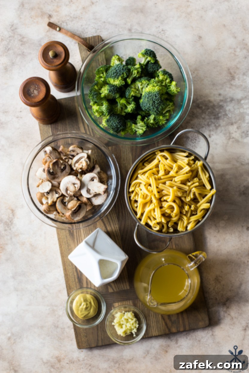 Creamy Garlic Pasta with Broccoli and Mushrooms 4 Overhead photo showcasing the fresh ingredients laid out for a creamy garlic broccoli mushroom pasta dish: broccoli florets, sliced mushrooms, garlic cloves, butter, heavy cream, and various seasonings.