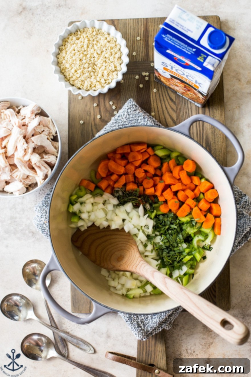 Overhead photo of a large pot filled with carrots, onions, celery and spices on a wooden board