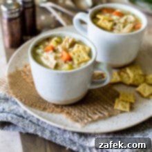 Lemony Chicken with Stars Soup in two mugs on a plate on a wooden board