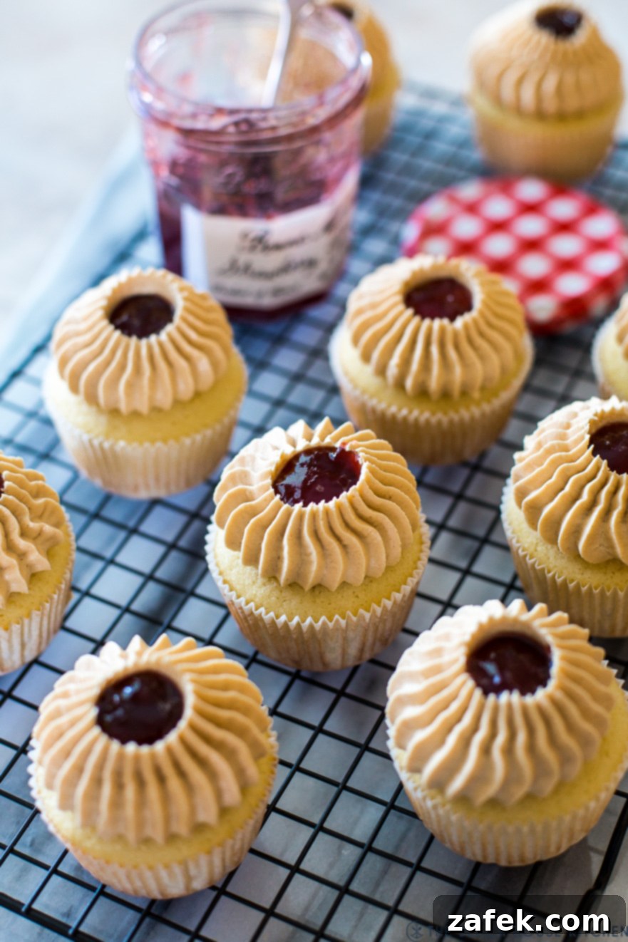 Peanut Butter and Jelly Cupcakes on a wire rack with a jar of preserves, showcasing their delightful appearance