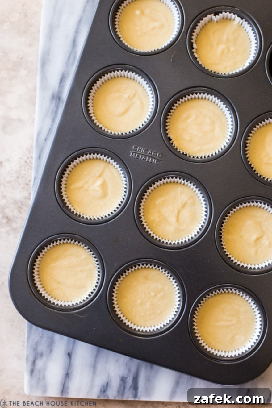 Overhead photo of unbaked vanilla cupcake batter in a cupcake tin, ready for the oven