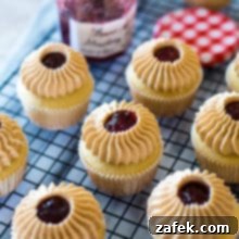 Peanut Butter and Jelly Cupcakes on a wire rack with a jar of strawberry preserves