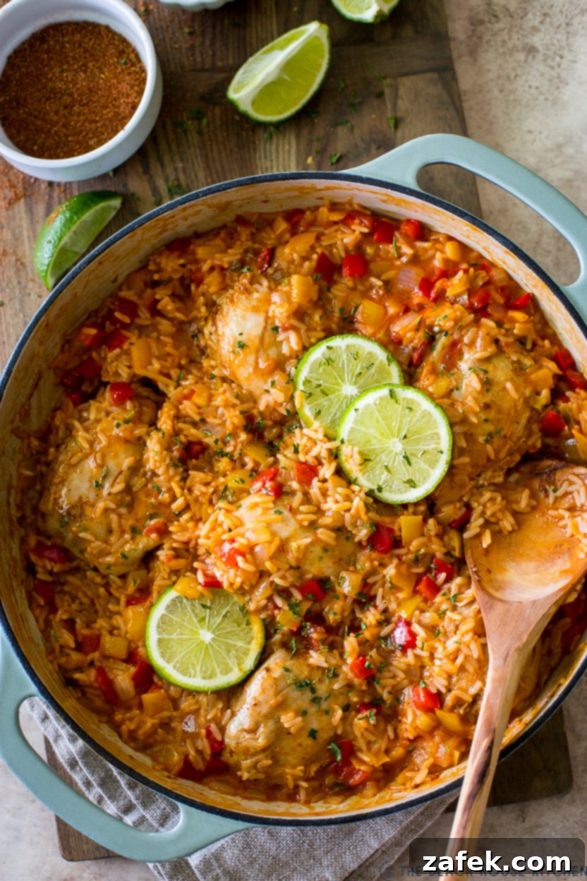 Up close overhead photo of a skillet of chicken and rice topped with lime slices