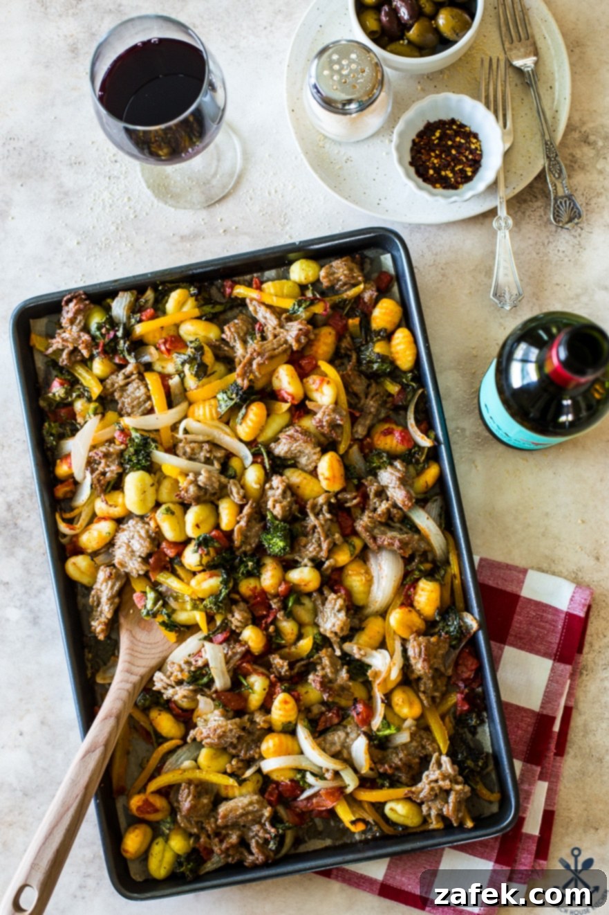 Overhead photo of a vibrant sheet pan dinner featuring gnocchi, Italian sausage, broccoli rabe, sliced onions, and bell peppers, cooked to perfection with a golden crisp.