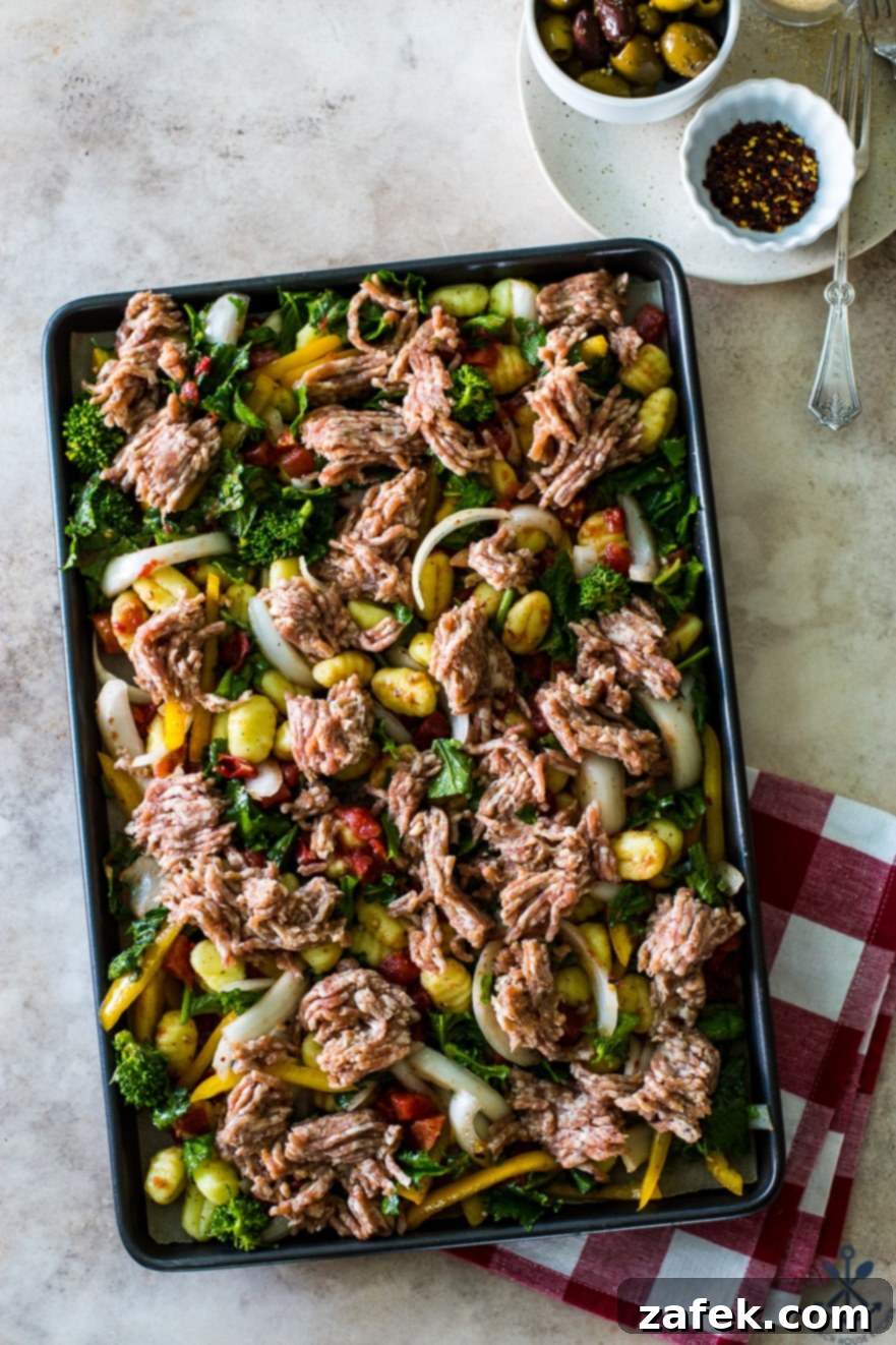 Overhead photo of the finished Sheet Pan Gnocchi with Italian Sausage, Broccoli Rabe, Onions, and Peppers in a serving dish, highlighting the appealing presentation and golden-brown roast.